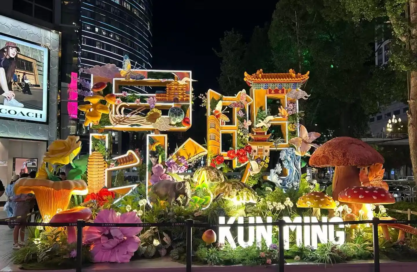 Night view of a vibrant illuminated garden sculpture display spelling 'Kunming' with flowers, mushrooms, and Chinese architectural elements in a city plaza at night.Nanping Commercial Street,Kunming,Yunnan ,Chinatravel