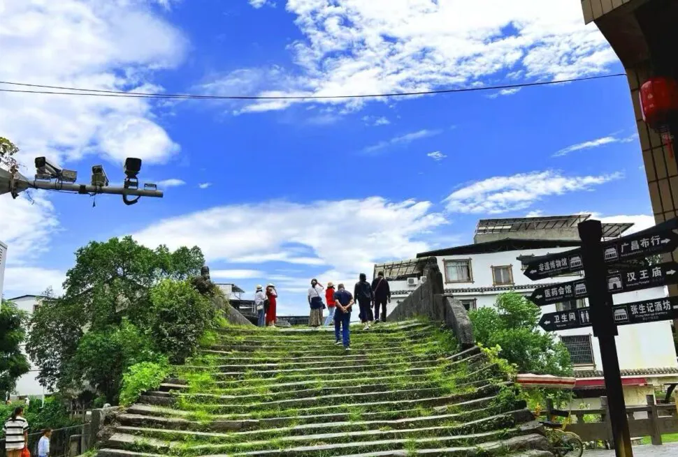 Group of visitors standing at the top of a mossy stone staircase under a bright blue sky.Daxu Ancient Town,Guilin,Guangxi ,Chinatravel