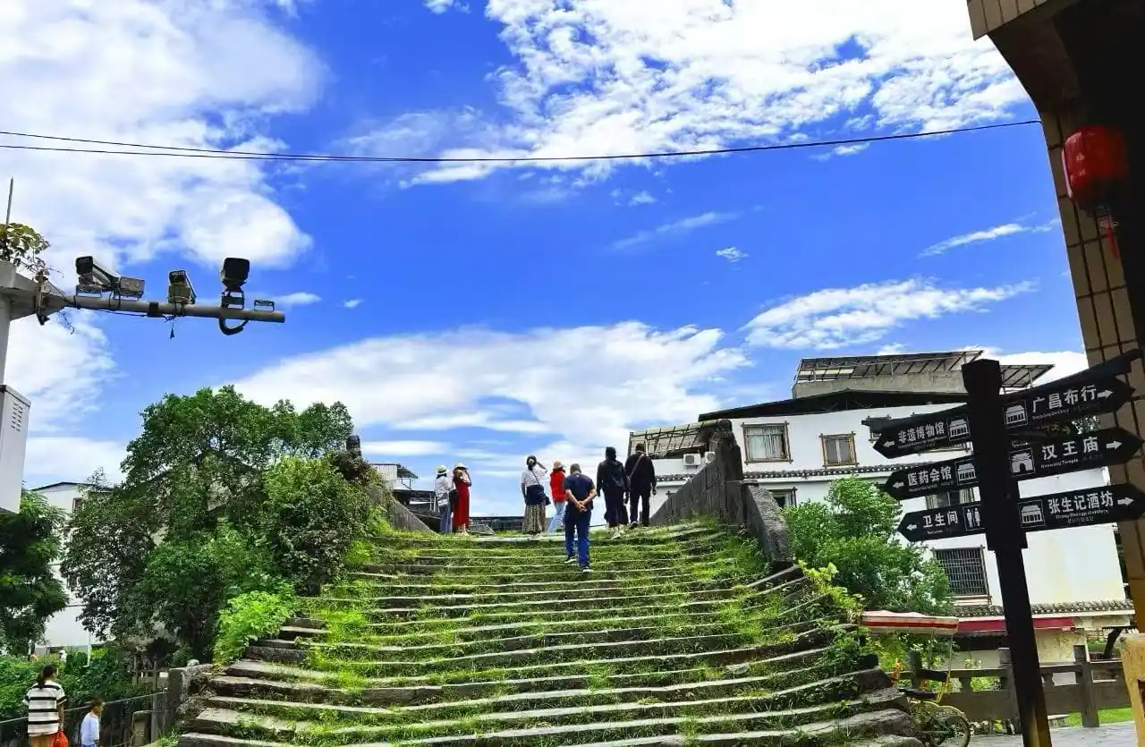 Group of visitors standing at the top of a mossy stone staircase under a bright blue sky.Daxu Ancient Town,Guilin,Guangxi ,Chinatravel