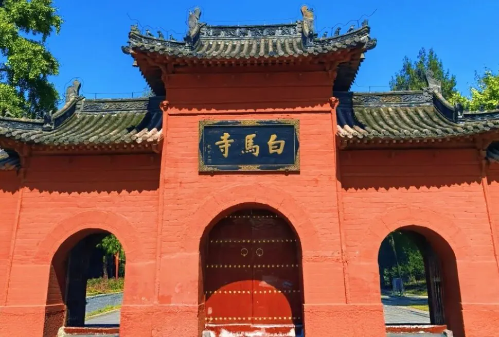White Horse Temple,Luoyang,Chinatour Red temple gate with curved gray-tiled roof, orange-red walls, and a central arched door beneath a black plaque with gold Chinese characters.