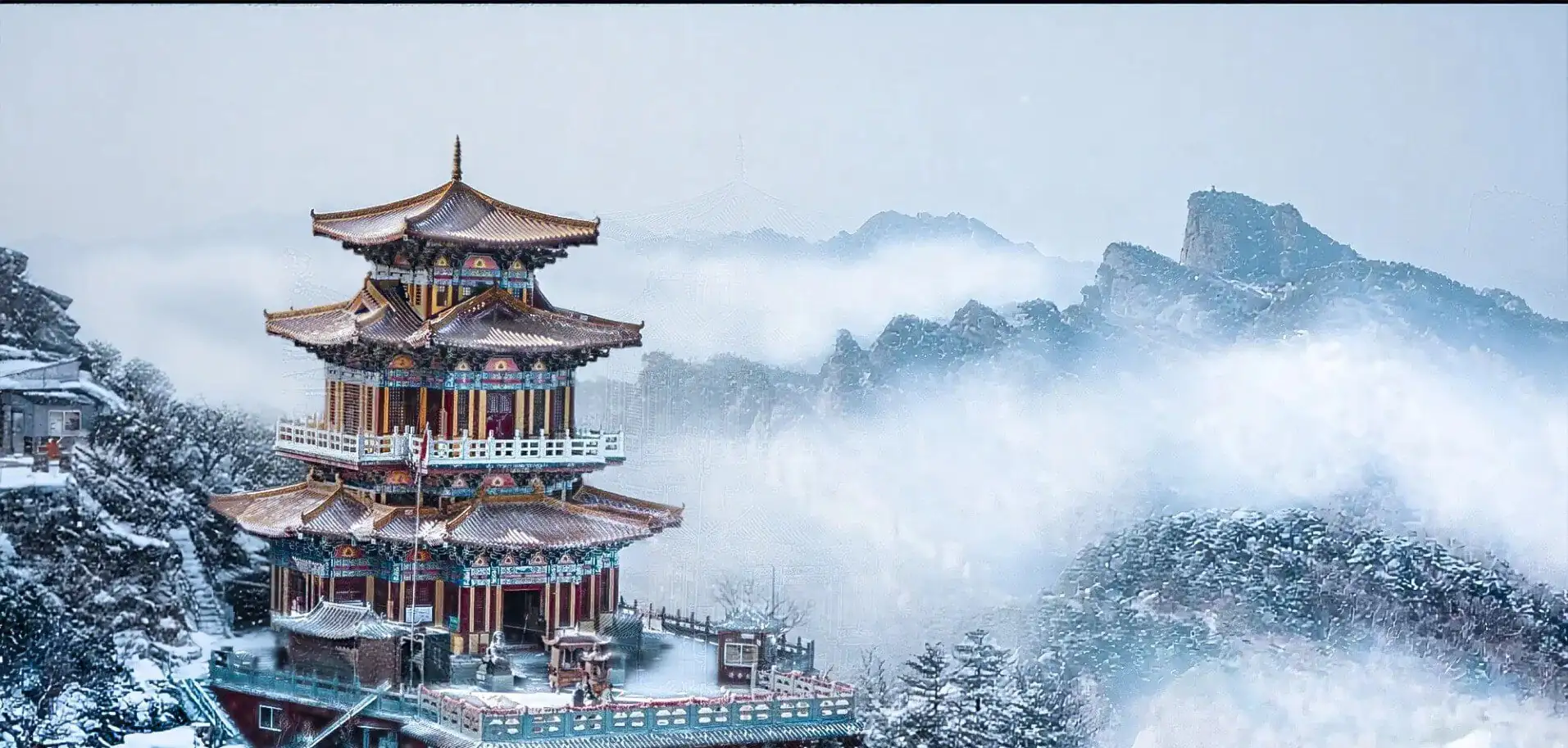 Baiyun Mountain Scenic Area,Luoyang,Chinatour Snow-covered Chinese pagoda perched on a hillside with misty mountains in the background.