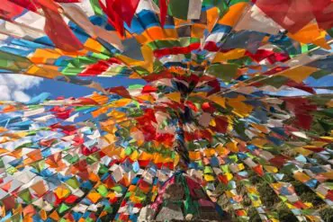 Vibrant multicolored prayer flags radiating from a central pole against a blue sky.Pudacuo National Park,Shangri-La,Yunnan,Chinatravel