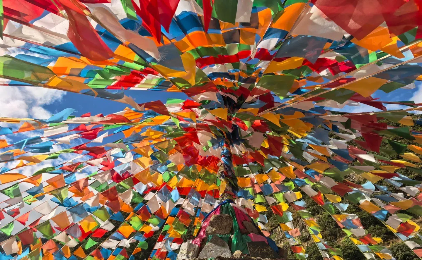 Vibrant multicolored prayer flags radiating from a central pole against a blue sky.Pudacuo National Park,Shangri-La,Yunnan,Chinatravel