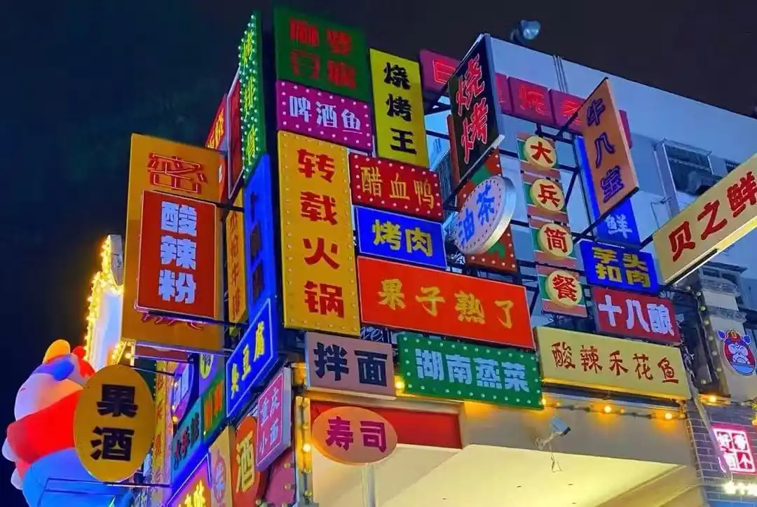 Bright neon restaurant signs with Chinese characters stacked on a corner building at night, creating a colorful storefront wall.Zhengyang Pedestrian Street,Guilin,Guangxi ,Chinatravel