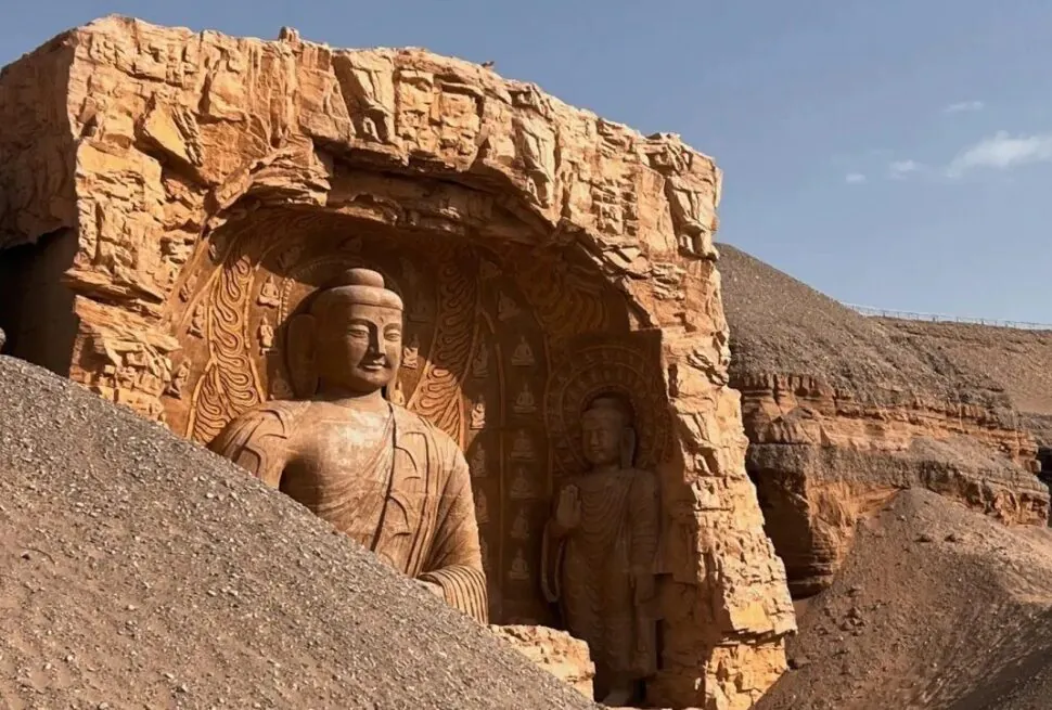 Two Buddhist statues carved into a sandstone cliff in a desert landscape, with a large statue foreground and a smaller one beside it in an arched niche.Dunhuang Mogao Caves,Dunhuang,Gansu