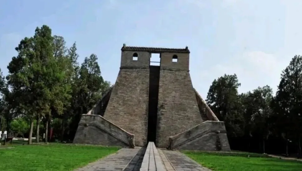 Stone pyramid-like monument with two flared staircases on either side and a central vertical opening, set in a green park with trees in the background.Star Observatory,Shaolin & Songshan Area,Henan,Chinatravel
