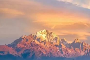 Snow-capped mountain range bathed in warm sunset light against a pastel sky,Jade Dragon Snow Mountain,Lijiang,Yunnan,Chinatravel