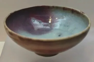 Henan Kaifeng Museum,Kaifeng,Henan,Chinatravel Handmade ceramic bowl with a glossy blue-green to purple glaze inside, viewed from the side on a neutral surface.
