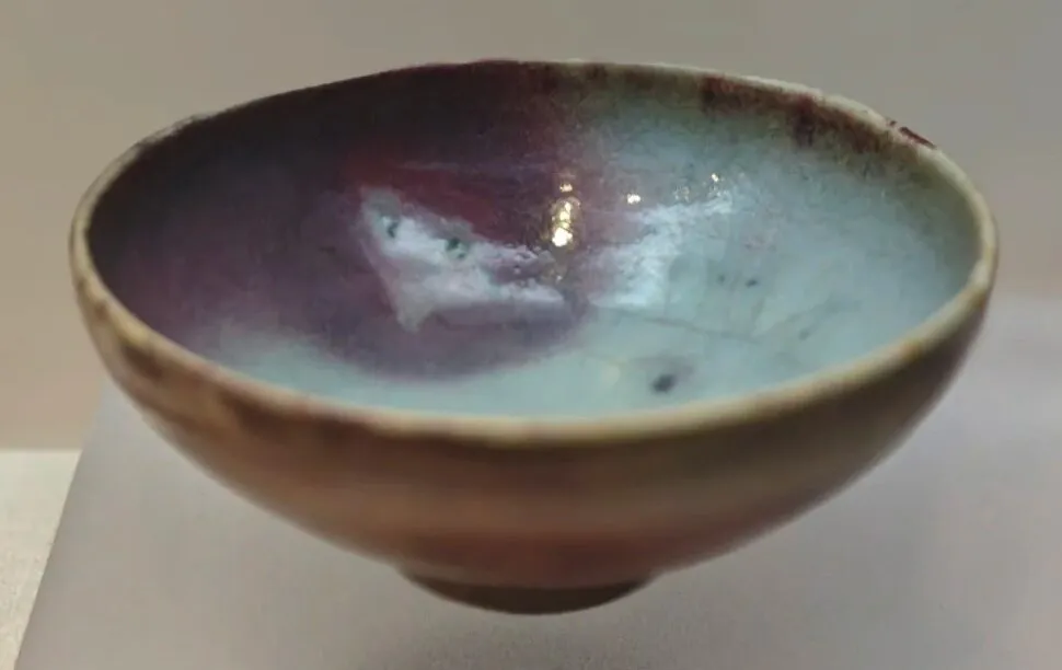 Henan Kaifeng Museum,Kaifeng,Henan,Chinatravel Handmade ceramic bowl with a glossy blue-green to purple glaze inside, viewed from the side on a neutral surface.