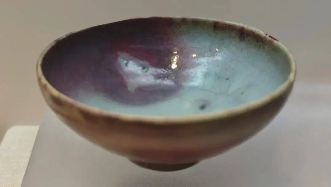 Henan Kaifeng Museum,Kaifeng,Henan,Chinatravel Handmade ceramic bowl with a glossy blue-green to purple glaze inside, viewed from the side on a neutral surface.