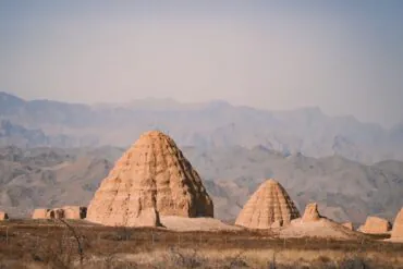Western Xia Imperial Tombs,Yinchuan,Ningxia,Chinatravel Desert landscape with large earthen pyramidal structures in the foreground and distant mountains on the horizon.