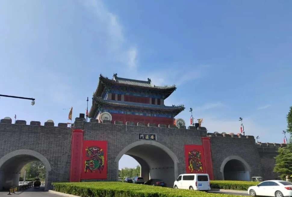 Kaifeng Ancient City Wall,Kaifeng,Henan,Chinatravel Traditional Chinese city gate with a multi-tier pagoda on top, gray brick walls, red banners, and arched entryways.