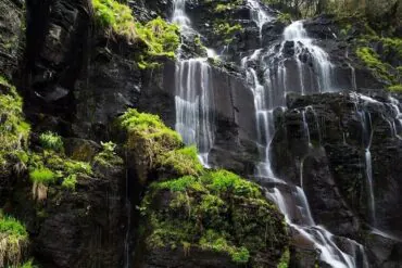 Lushuihe National Forest Park,Baishan,Jilin,Chinatravel Cascade of waterfalls flowing over dark rocks with lush green vegetation on a cliffside.