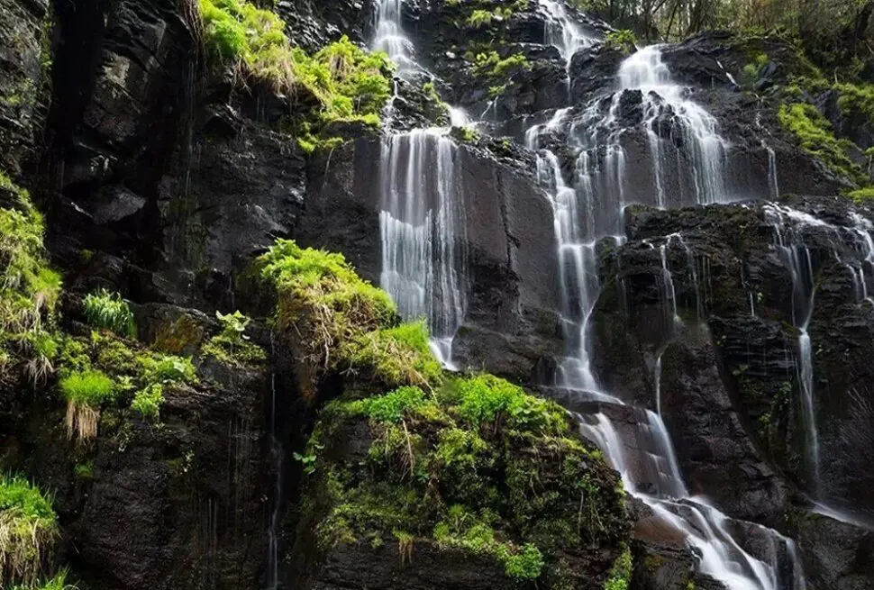 Lushuihe National Forest Park,Baishan,Jilin,Chinatravel Cascade of waterfalls flowing over dark rocks with lush green vegetation on a cliffside.