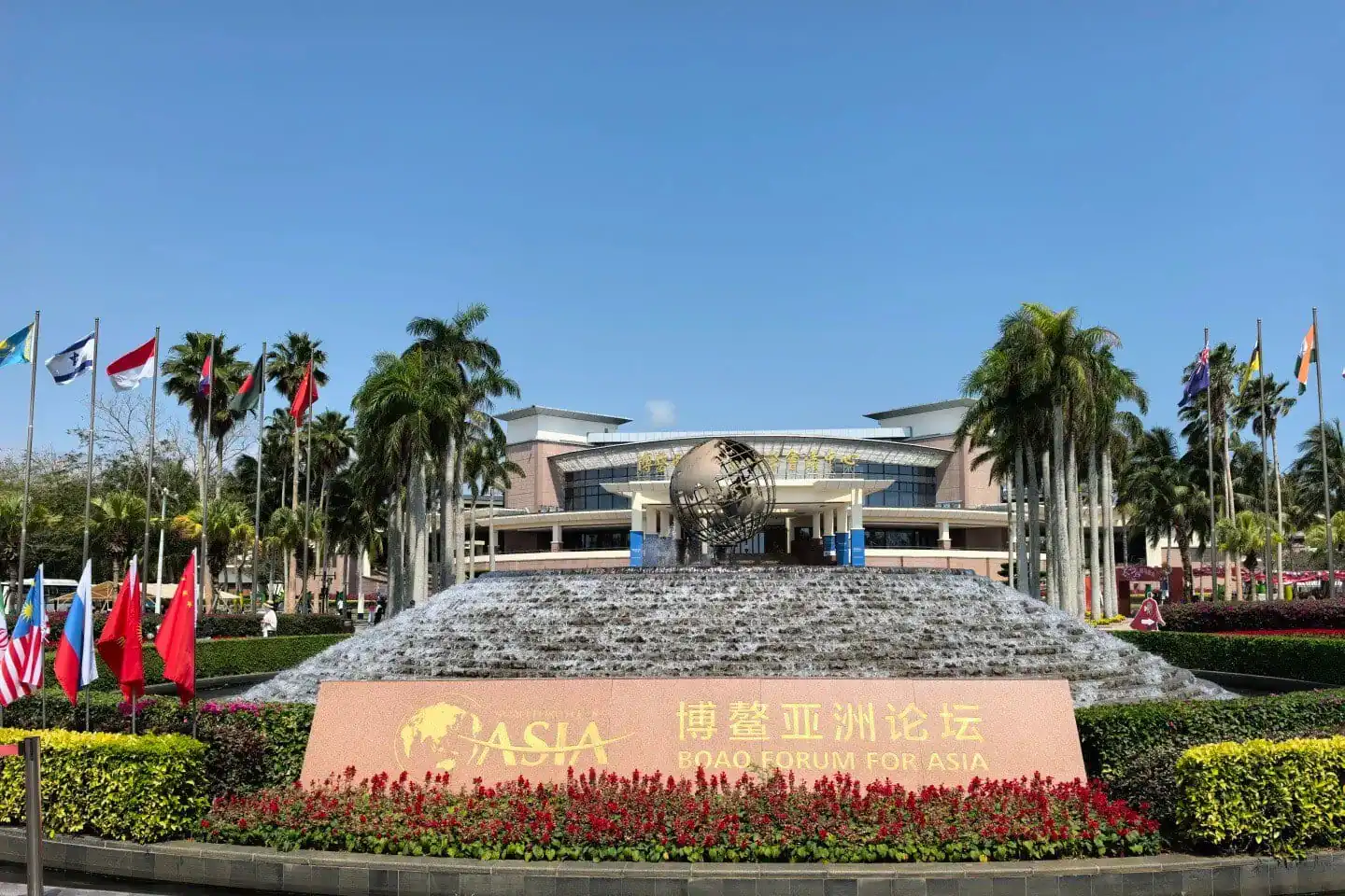 Bo’ao Forum for Asia Conference Center,Qionghai,Hainan,Chinaexplorertour Boao Forum for Asia sign in front of a tiered fountain and globe sculpture, with flags and palm trees.