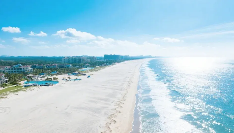 Silver Beach,Beiahi,Guangxi,Chinaexplorertour Aerial view of a sunny beach with white sand, turquoise ocean, and resort buildings along the shore.