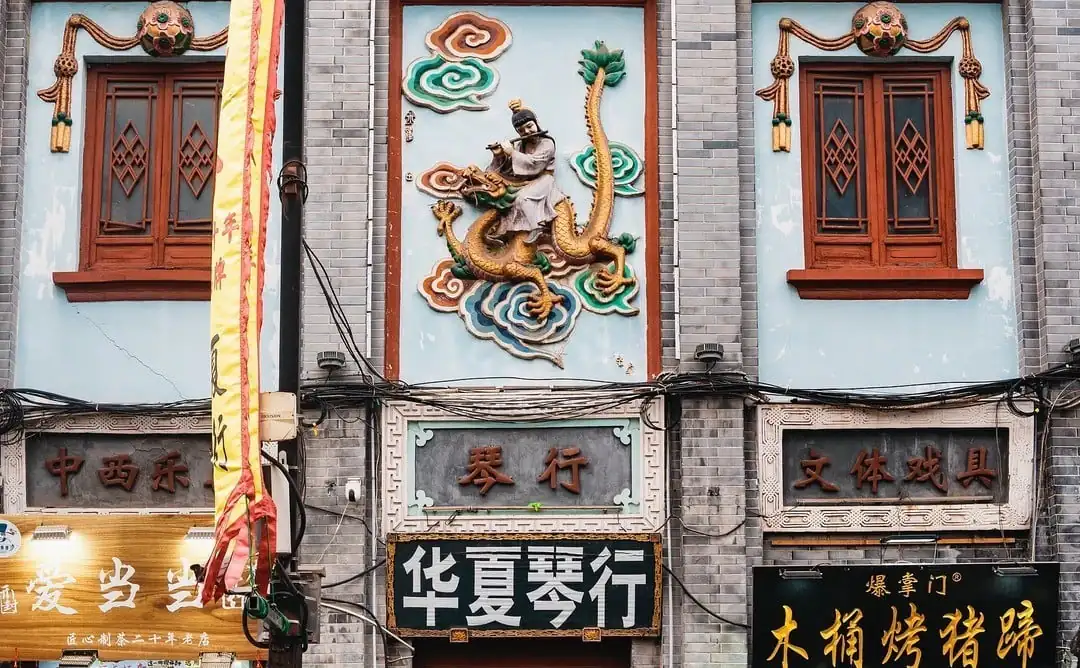 Bookstore Street,Kaifeng,Henan,Chinatravel Facade of a Chinese storefront row with a dragon mural above the entrance, ornate windows, and Chinese signs below.