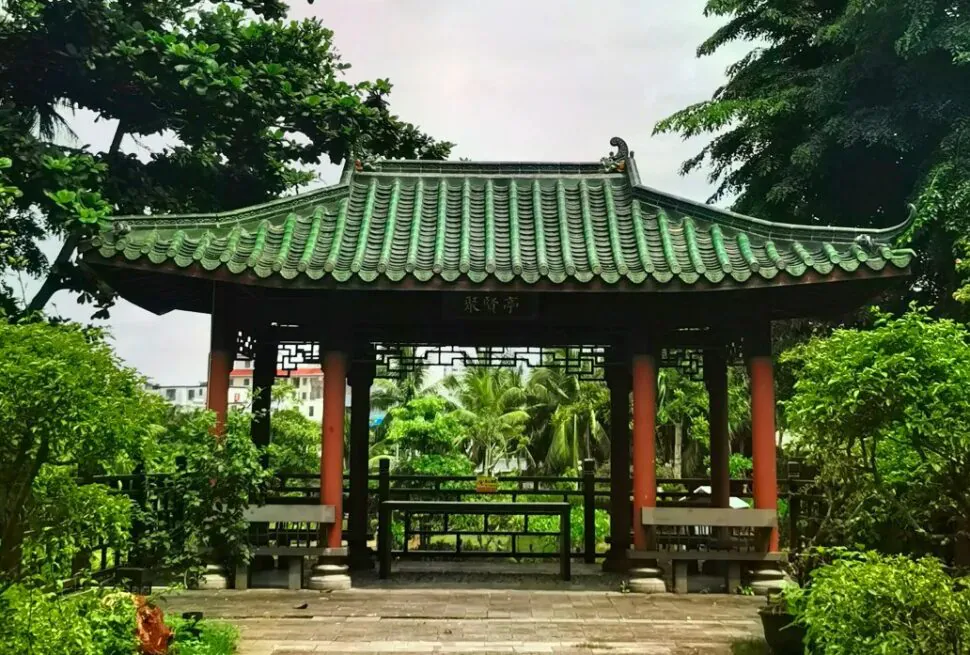 Temple of the Five Lords,Haikou,Hainan,Chinaexplorertour Traditional Chinese pavilion with a green-tiled roof and red pillars in a lush garden setting.