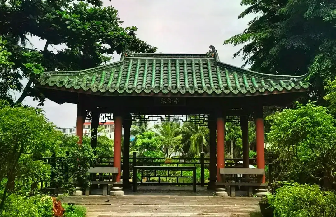 Temple of the Five Lords,Haikou,Hainan,Chinaexplorertour Traditional Chinese pavilion with a green-tiled roof and red pillars in a lush garden setting.