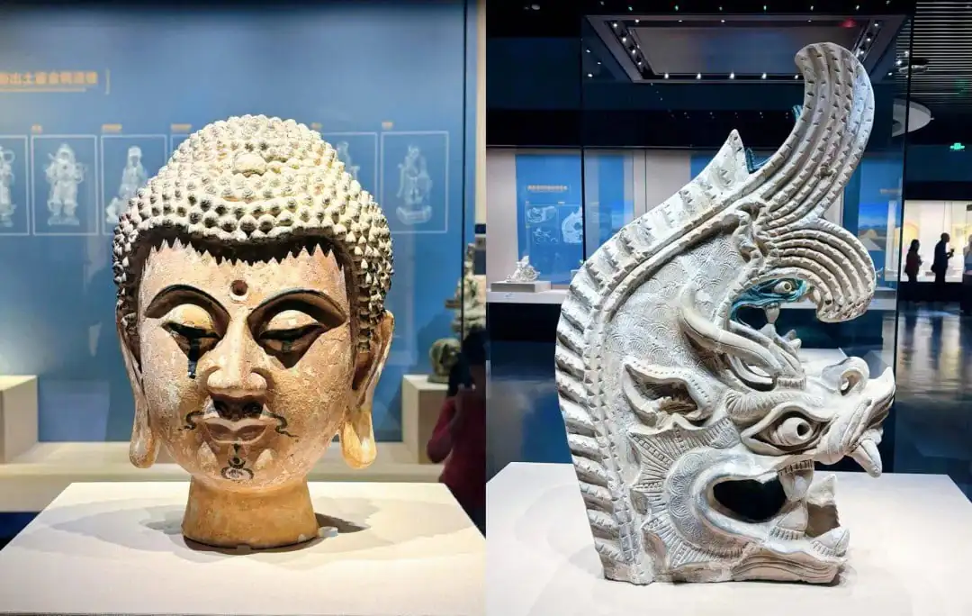 Ningxia Museum,Yinchuan,Ningxia,Chinatravel Two museum sculptures: left a tranquil Buddha head with textured hair; right an ornate dragon head carving with an open mouth and detailed patterns.