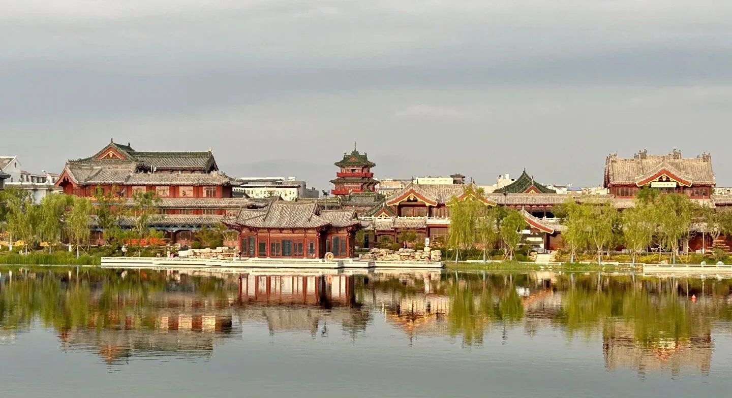 Baogong Lake & Park,Kaifeng,Henan,Chinatravel Traditional Chinese temple complex along a calm lake with reflections in the water and trees lining the shore.