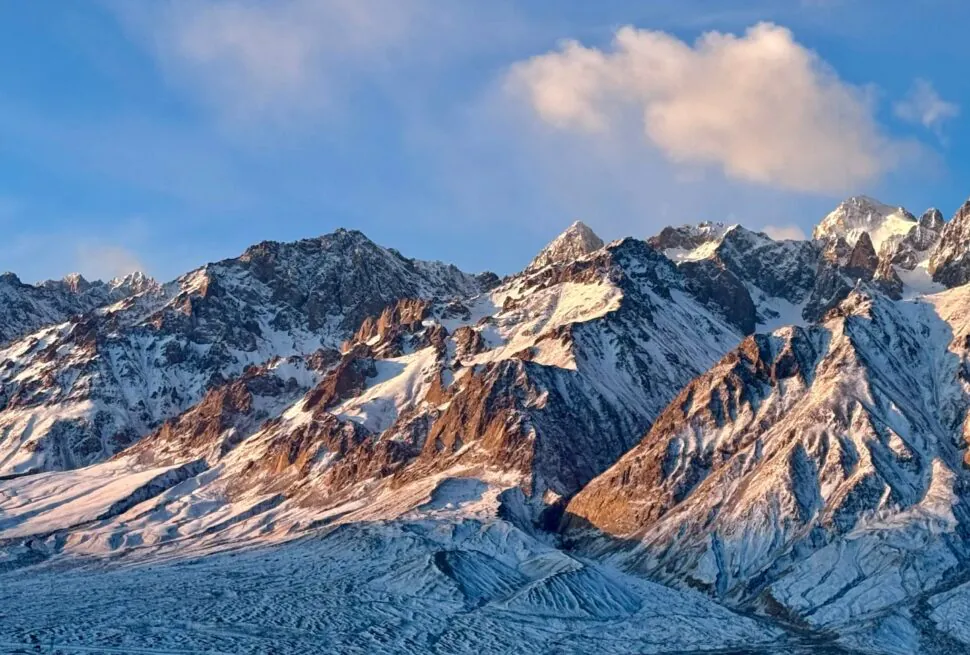 Pamir Plateau (Tashkurgan),Kashgat,China tour Snow-covered jagged mountain range under a blue sky with a few clouds.