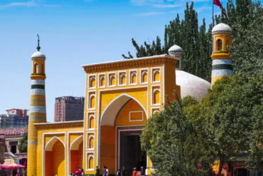 Colorful mosque entrance with yellow and orange tiles, minarets, and a flag in the background,Id Kah Mosque,Kashgar,Xinjiang,Chinatravel