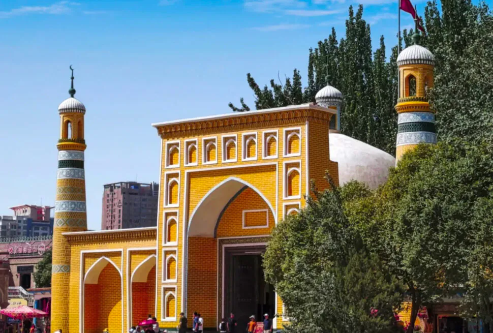 Colorful mosque entrance with yellow and orange tiles, minarets, and a flag in the background,Id Kah Mosque,Kashgar,Xinjiang,Chinatravel