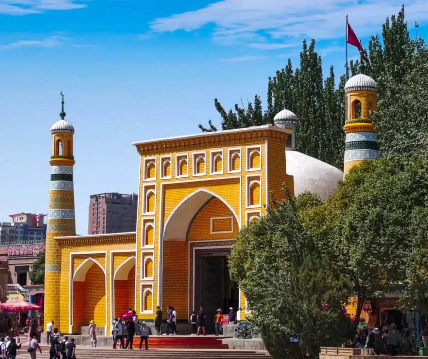 Colorful mosque entrance with yellow and orange tiles, minarets, and a flag in the background,Id Kah Mosque,Kashgar,Xinjiang,Chinatravel