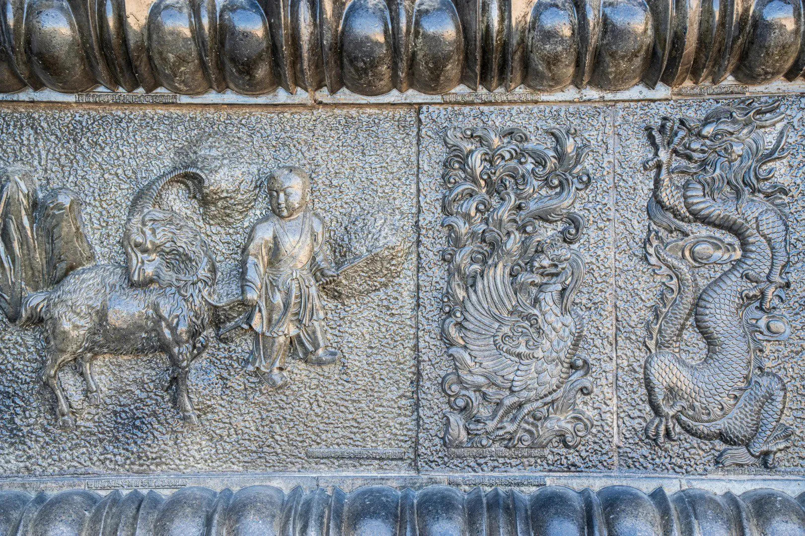 Detailed stone relief with dragons, phoenixes, and historical figures in Chinese art.