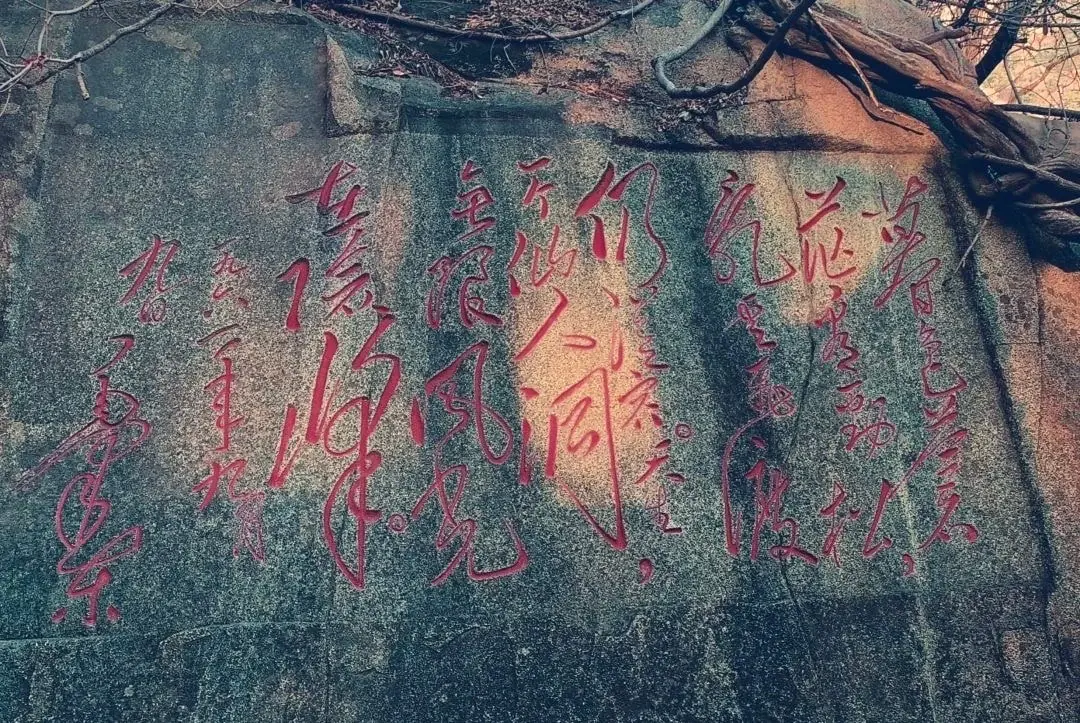 A scenic rock wall with traditional Chinese calligraphy inscriptions in red ink.