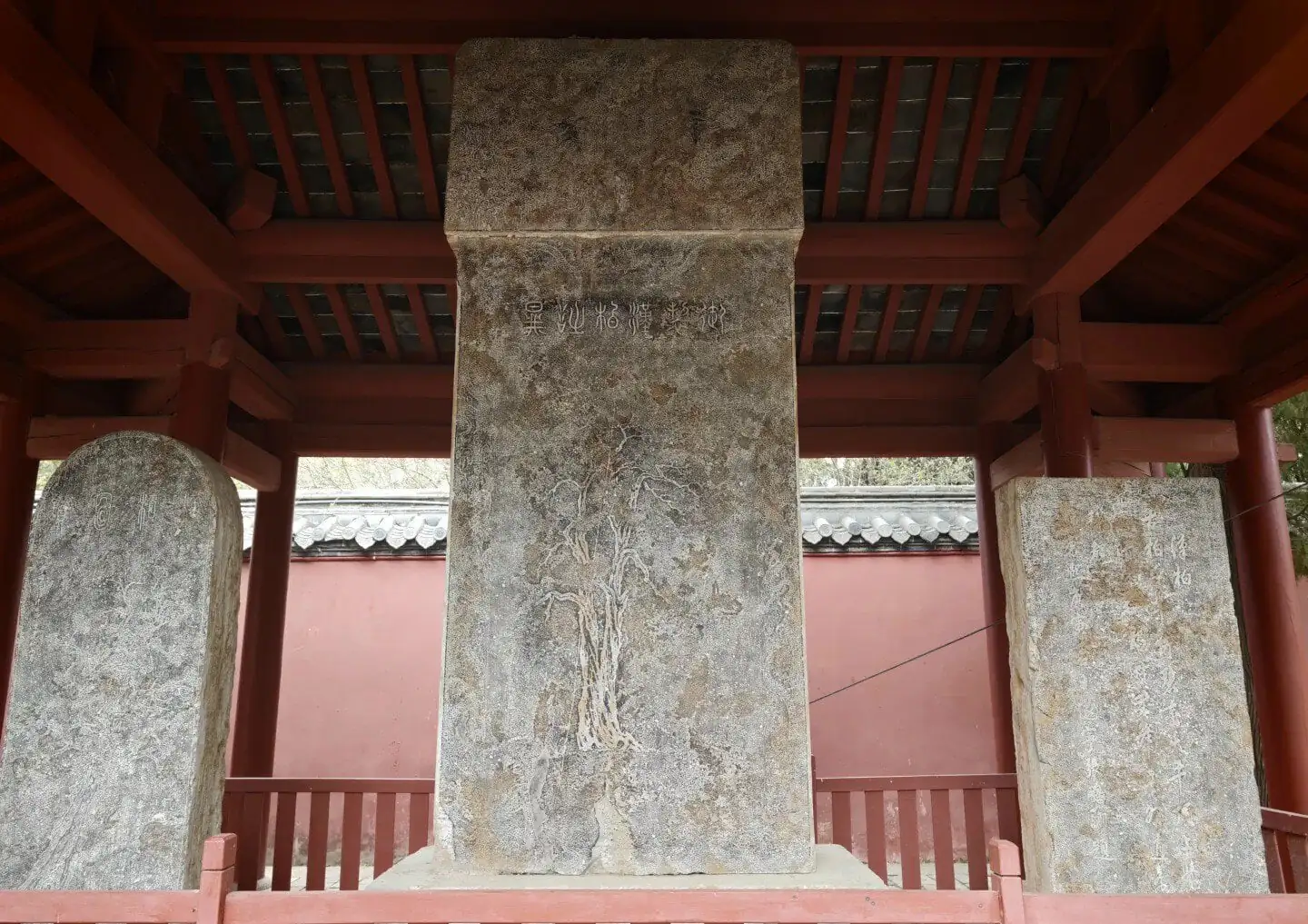 Ancient stone steles inside a traditional Chinese temple with wooden beams and red pillars.