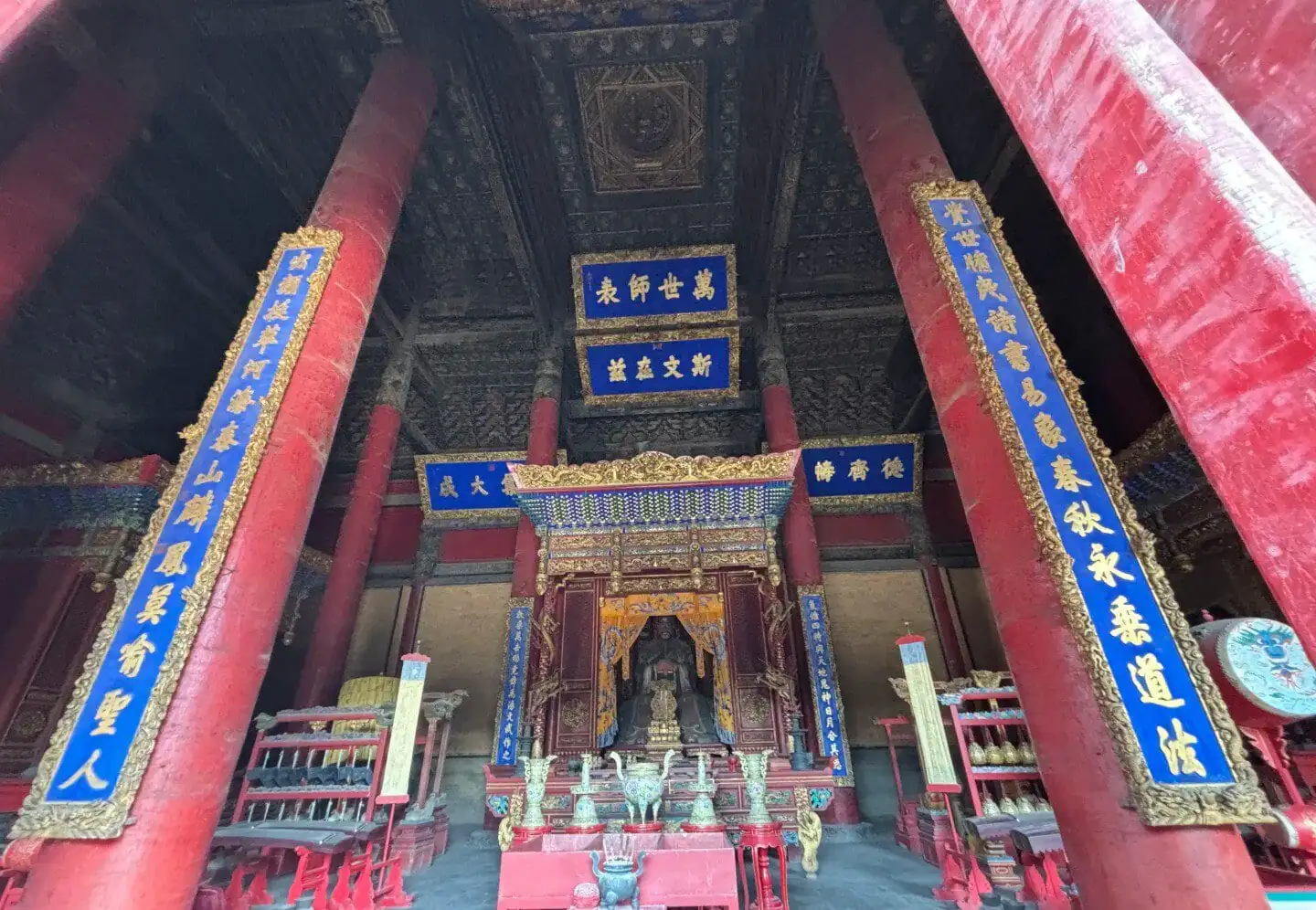 Ancient Chinese temple interior with red columns and traditional decorations.