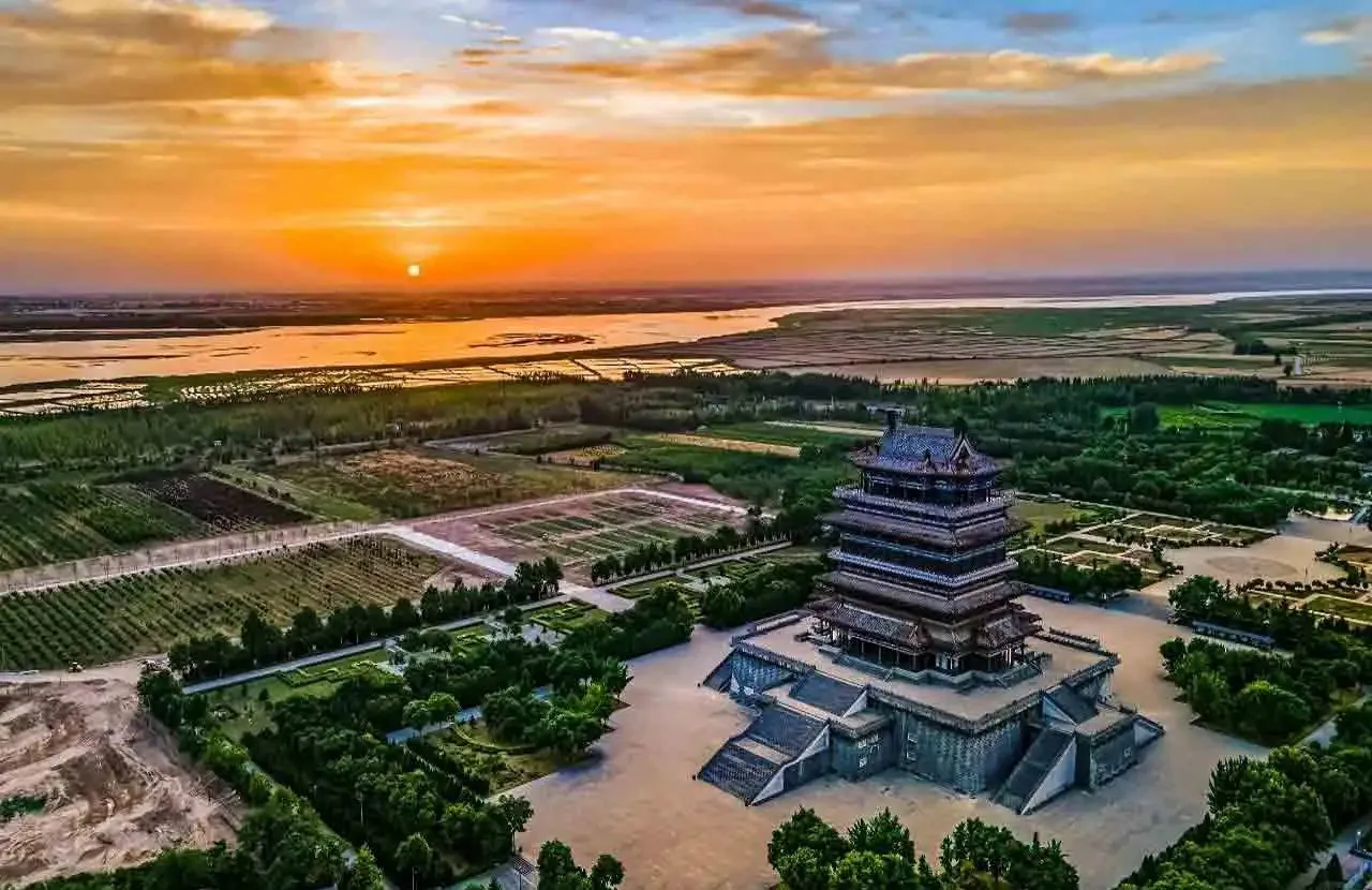 A multi-tier pagoda-style temple complex at sunset, surrounded by gardens and fields,Stork Tower,Yuncheng,Shanxi