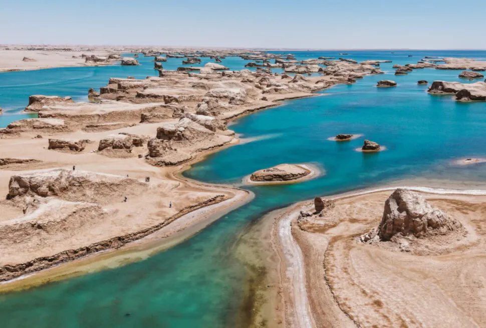 Desert coastline with turquoise tidal pools and layered rock formations under a clear blue sky,Wusute Water Yadan,Haixi Prefecture,Qinghai ,Chinatravel