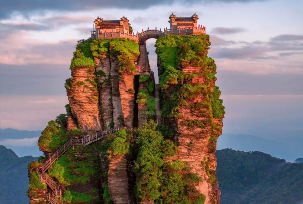 Tall rock pillar topped with traditional-style buildings, connected by stairways and lush greenery, overlooking a distant valley.Fanjing Mountain,Tongren,Guizhou