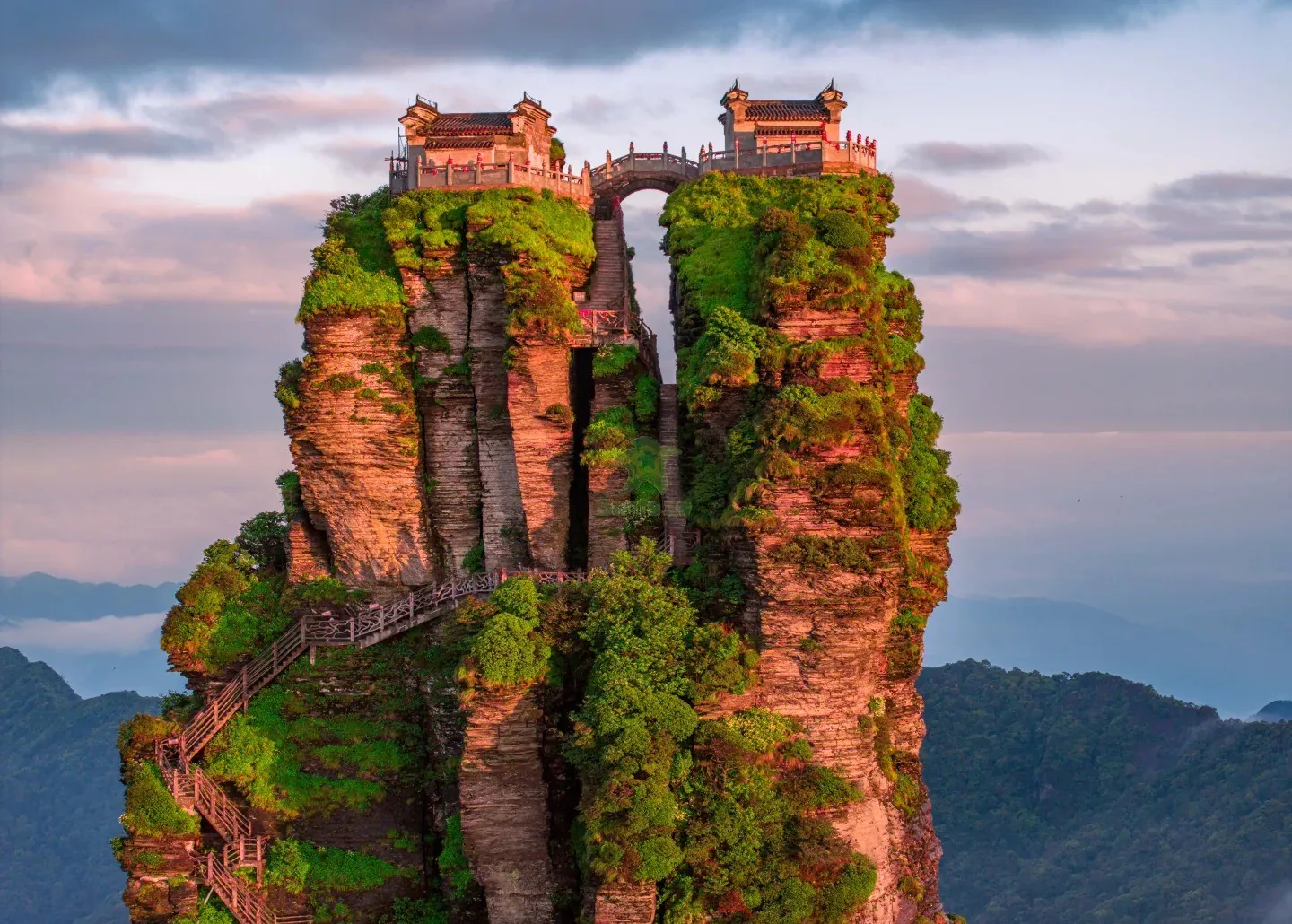 Tall rock pillar topped with traditional-style buildings, connected by stairways and lush greenery, overlooking a distant valley.Fanjing Mountain,Tongren,Guizhou