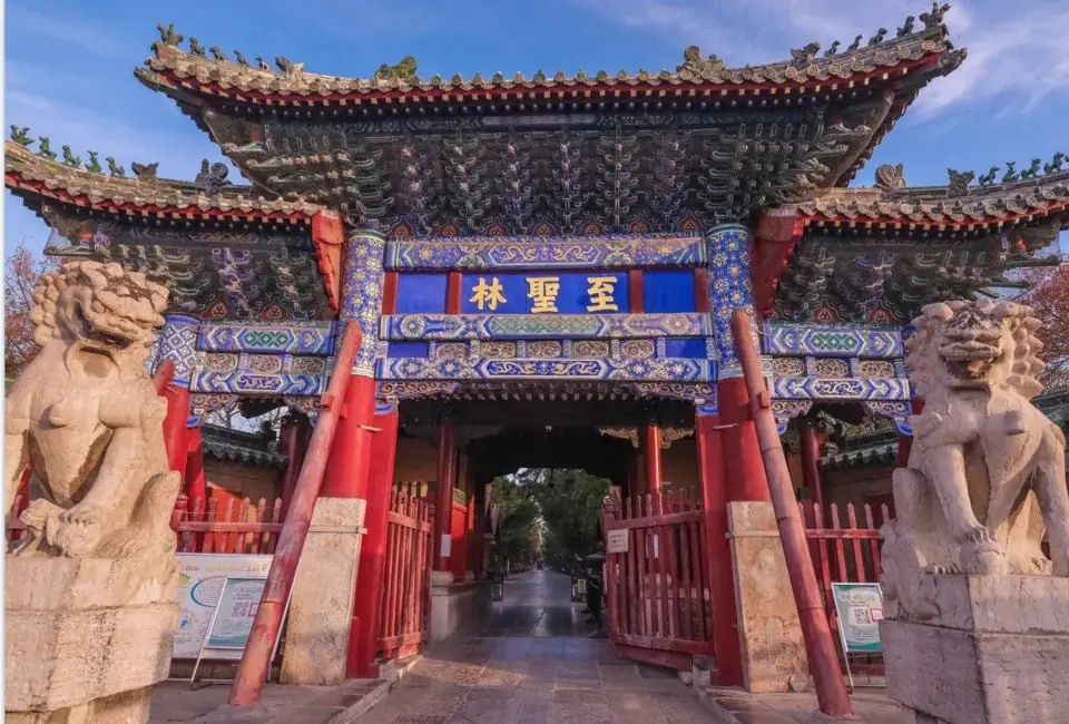 Ancient Chinese temple gate with stone lion statues and traditional architecture.