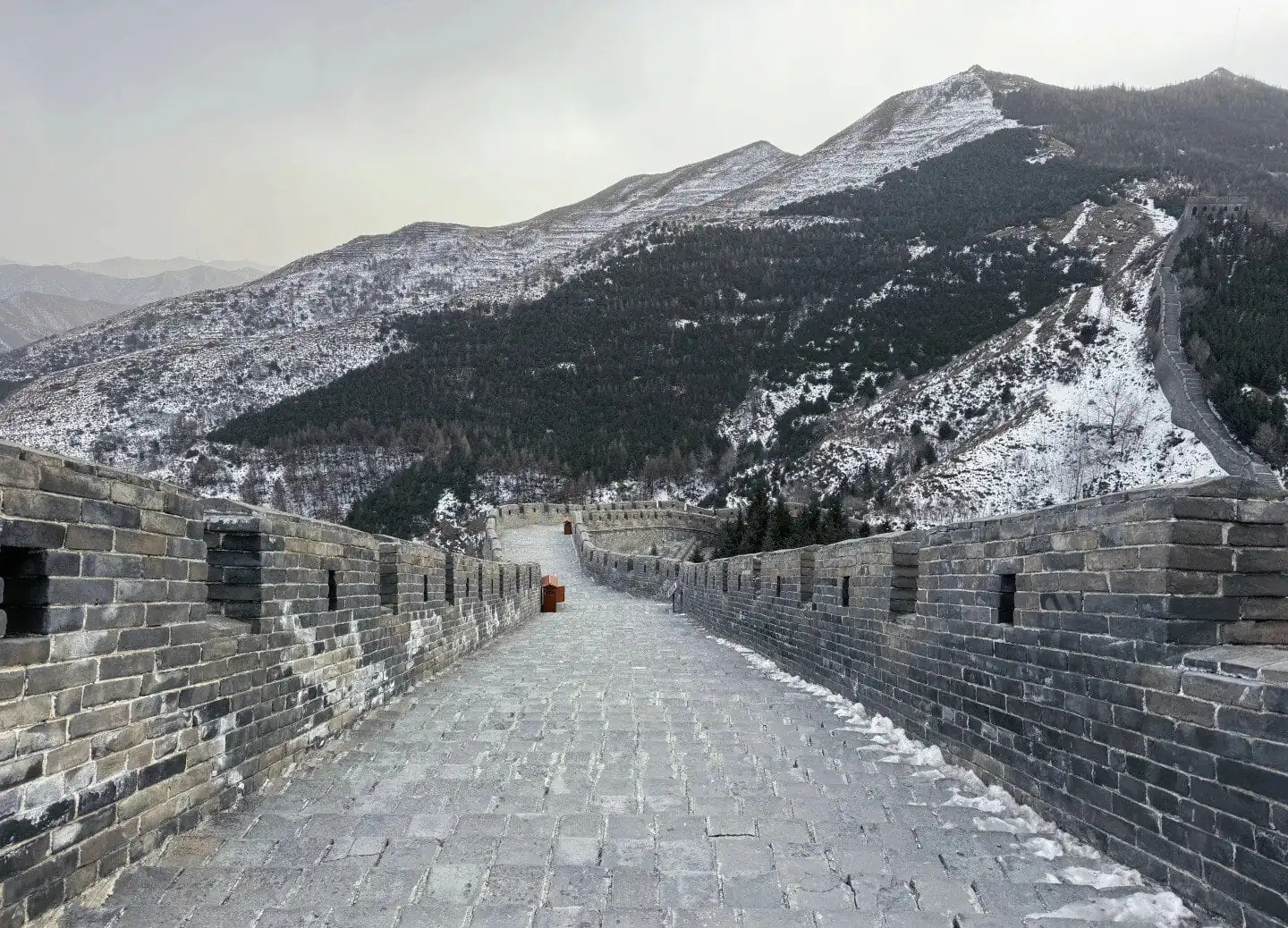The Great Wall of China extending over snow-covered mountains in winter.