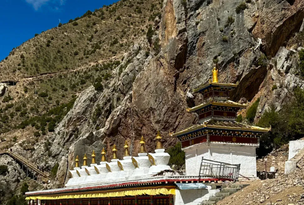 Tiered Buddhist temple built into a rocky mountainside with gold finials and a blue sky above.Princess Wencheng Temple,Yushu, Qinghai
