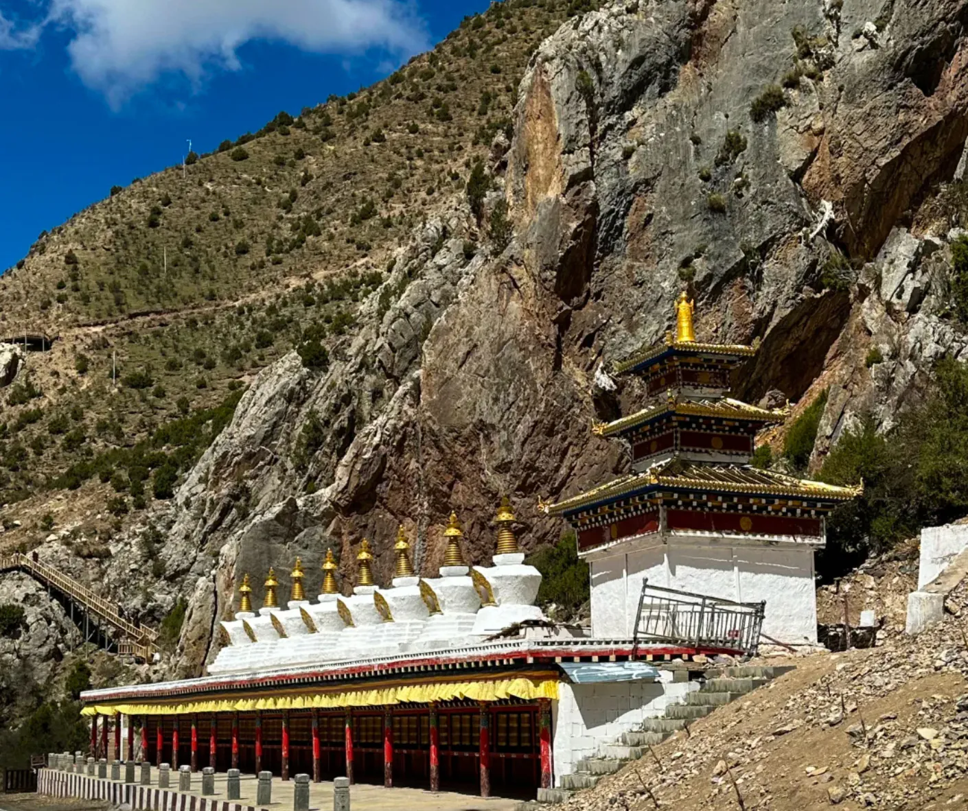 Tiered Buddhist temple built into a rocky mountainside with gold finials and a blue sky above.Princess Wencheng Temple,Yushu, Qinghai