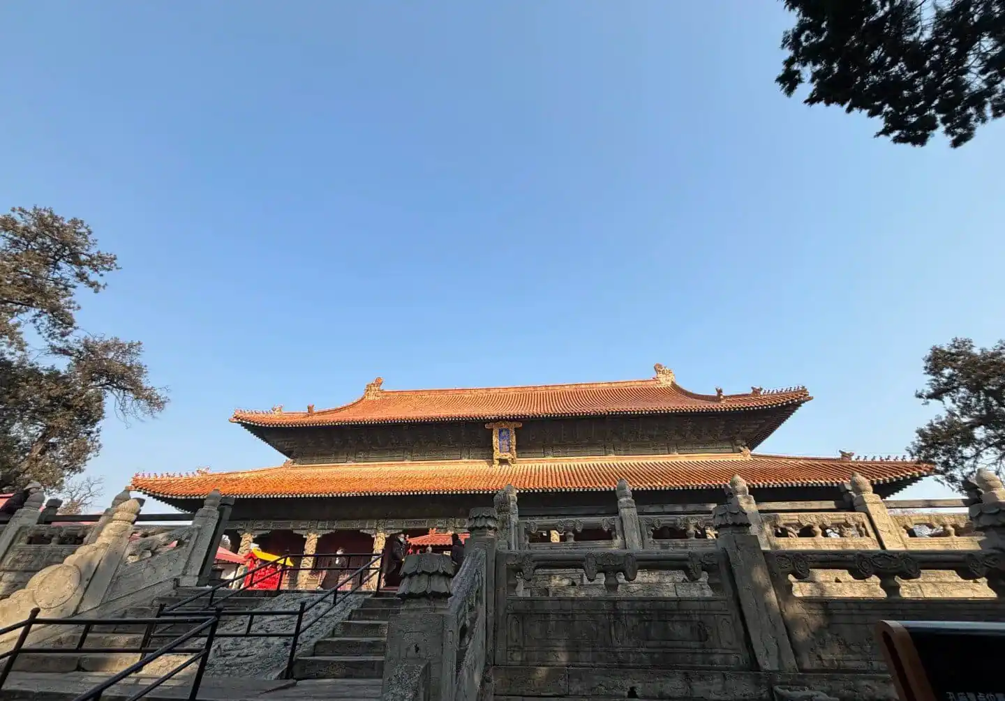 Ancient Chinese temple with traditional architecture and red-tiled roof under a clear blue sky.