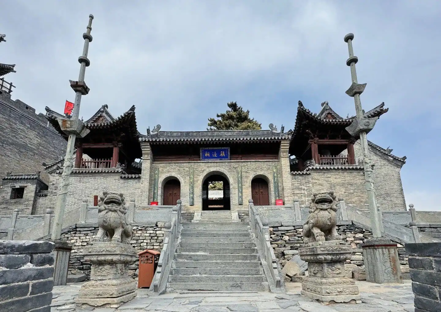 Stone steps leading to a traditional Chinese temple with lion statues and ornate roof details.