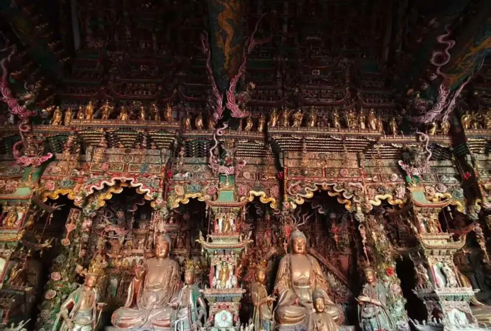 Intricately carved, colorful shrine with multiple Buddha statues inside a richly ornamented temple hall,Xiaoxitian Hanging Temple,Linfen,Shanxi