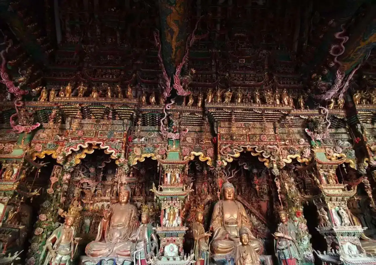 Intricately carved, colorful shrine with multiple Buddha statues inside a richly ornamented temple hall,Xiaoxitian Hanging Temple,Linfen,Shanxi