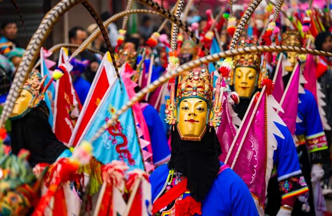 Masked performer in a bright blue outfit with a gold ornate mask leads a colorful festival parade.Anshun Tunpu Cultural Scenic Area ,Anshun,Guizhou