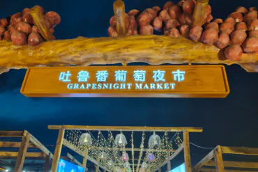 Turpan Night Market,Turpan,Chinatour Grapesnight Market sign with hanging lights and visitors at night in China.