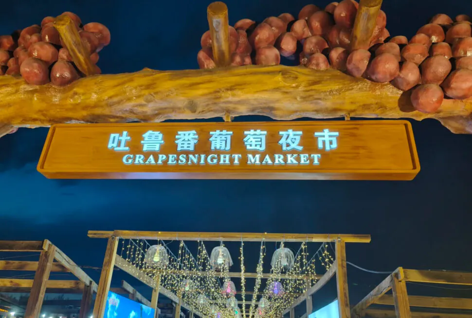 Turpan Night Market,Turpan,Chinatour Grapesnight Market sign with hanging lights and visitors at night in China.