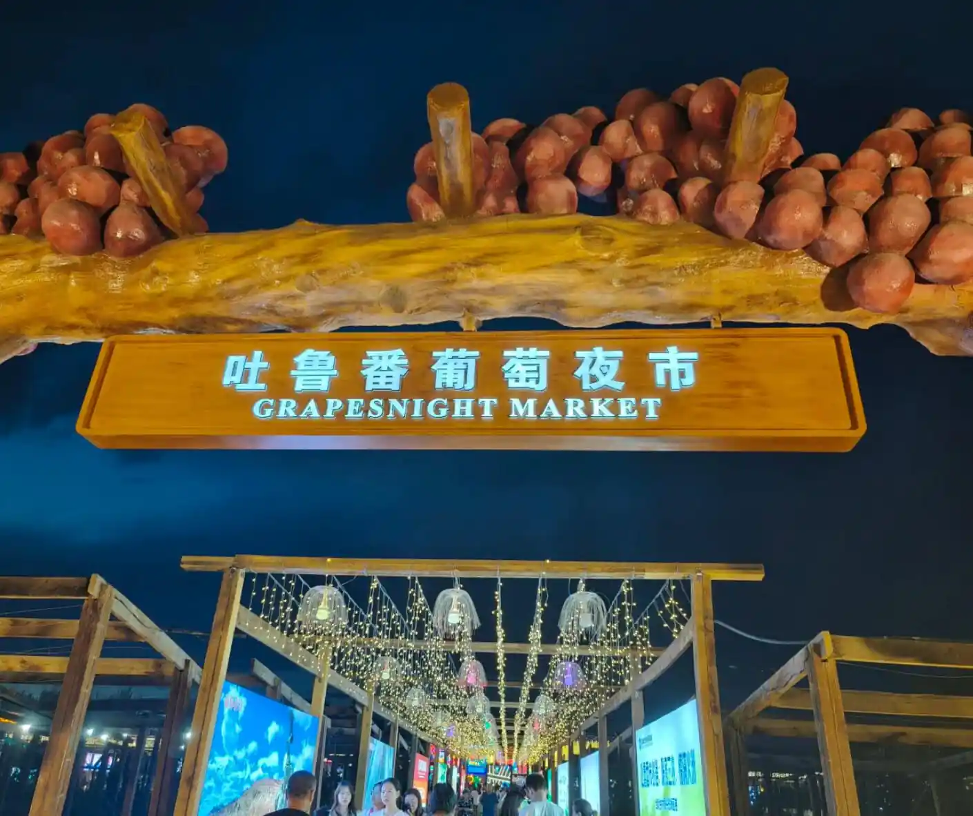 Turpan Night Market,Turpan,Chinatour Grapesnight Market sign with hanging lights and visitors at night in China.