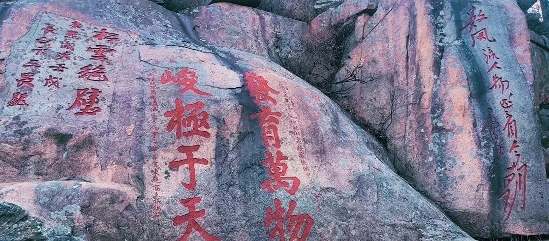 Ancient Chinese rock with red calligraphy inscriptions at a cultural site in China.